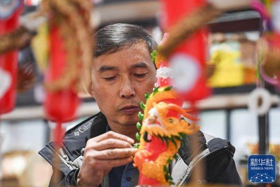 ↑1月25日,陈建友在工作坊制作龙凤花烛产品。
