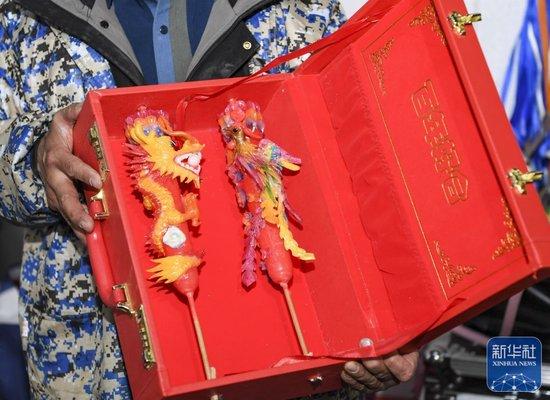 ↑1月24日,陈建友在工作坊展示龙凤花烛产品。