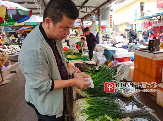 淡村市场食品安全部负责人陆发军正在用纸巾擦拭葱。