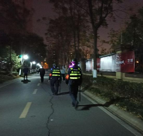 ▲11月23日19时,两名保安正拿着警棍在小区内巡逻。 新京报记者 吴梦真 摄