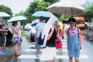 艺苑路上,没带雨伞的市民只能用衣裳遮头暂避。 信息时报记者 梁钜聪 摄