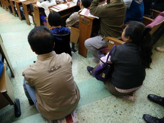 来晚的家长没座位就坐在地上。