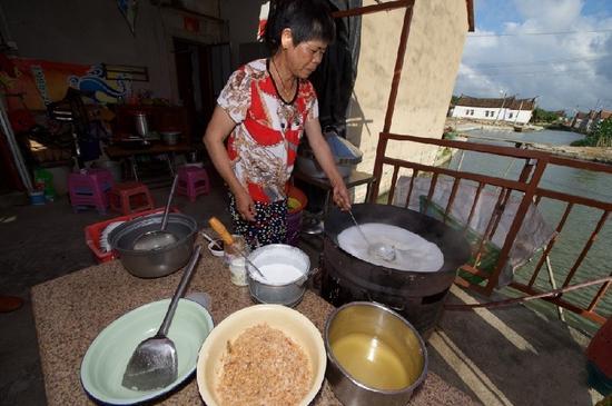 5月27日,埭美村一位经营小吃店的村民在为游客做当地美食“锅边糊”