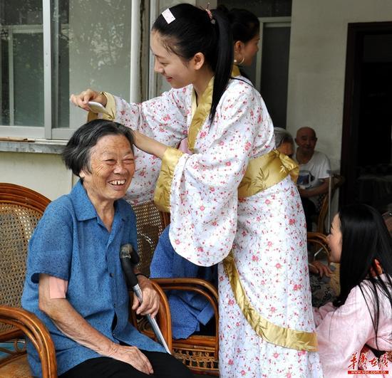 “十三村”品牌形象代言人候选人为光荣院老人梳头发。