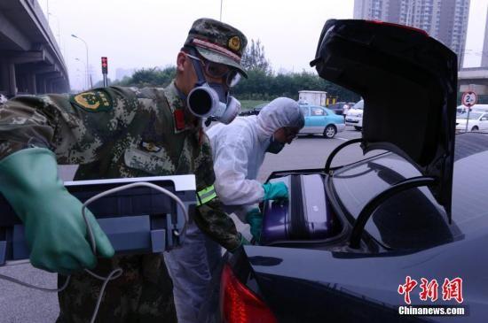 距离天津港爆炸现场最近的小区居民回家取东西,图为8月18日下午,一位武警士兵帮助身穿防护服的居民搬运家用电器。