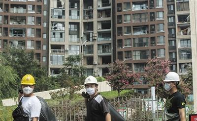 8月14日,天津滨海新区,人们走过被爆炸波及的居民楼。新京报记者 彭子洋 摄