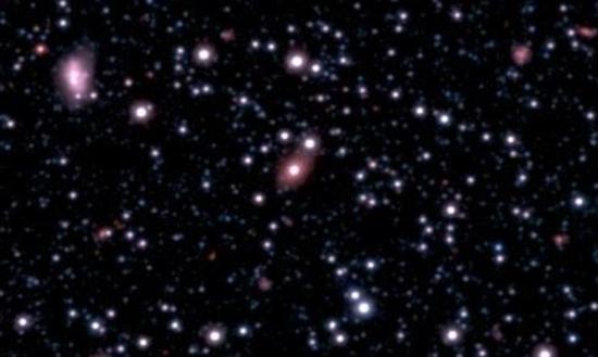 新发现的星系SAGE0536AGN(图像中央粉色椭圆星系)被发现其中心存在一个超大质量黑洞,并且其质量远超天文学家们的预期。这个黑洞的成长速度似乎远远超出了它的宿主星系