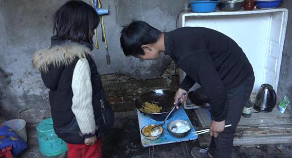 4月3日放学以后,曲比(右)和妹妹自己做晚饭。虽然只有一道菜炒土豆丝,但兄妹俩依旧吃得津津有味。澎湃新闻记者记者 朱莹 图