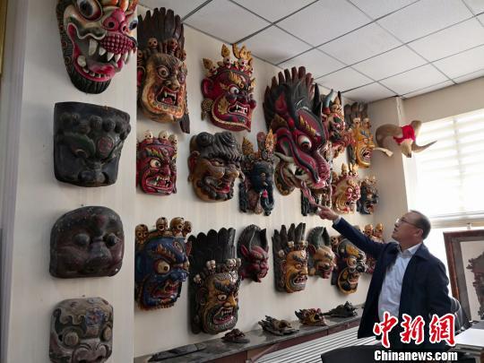 图为贾森栋和他收藏的傩面具。 刘薛梅 摄