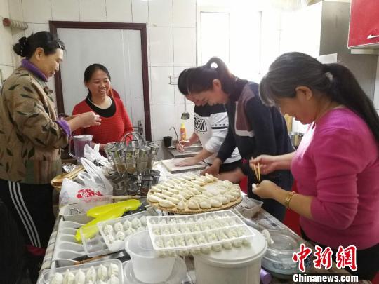 在厨房内,廉女士和家长们正在用从家里准备好的面和馅为理查德包饺子。 杨杰英 摄