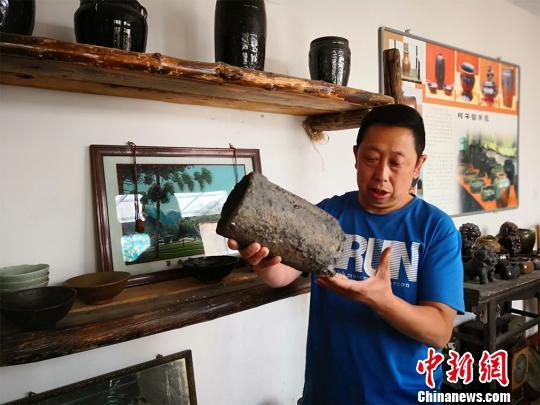 图为彭维国展示他从村里废墟上淘来的冶铁工具。 魏建军 摄