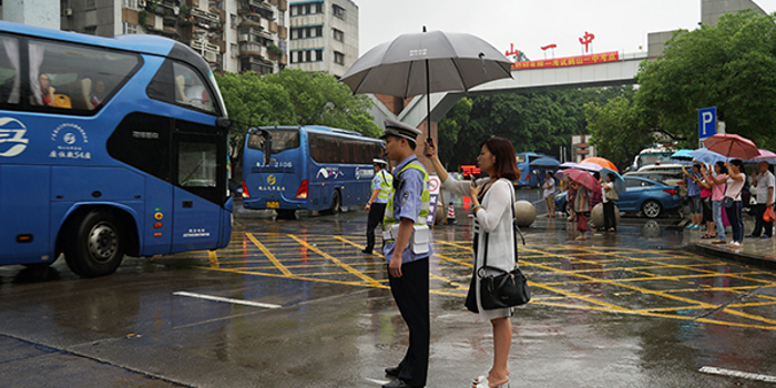 暖闻|广东江门一高考考场前交警冒雨指挥交通