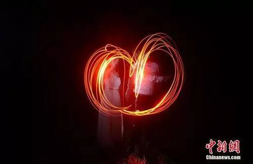 情侣湖南湄江拍创意光绘照迎“七夕”,情侣用手电筒画出了心形的图案。杨华峰 摄