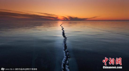 2015年4月1日消息,俄罗斯贝加尔湖面结冰,数百米长的裂缝仿佛将世界一分为二,夕阳的余晖洒在湖面上景色神奇迷人。图片来源:CFP视觉中国