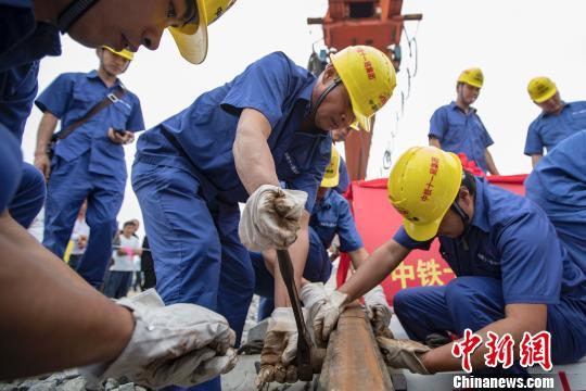 图为,9月21日,建设者在湖北省潜江市境内江汉铁路潜江北站进行最后一排钢轨铺设作业。 徐云华 摄