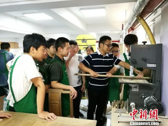 负责指导的王坚老师正在教导学生用机器加工木材。 钟升 摄