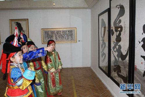 资料图:2011年11月,在蒙古国首都乌兰巴托,几名儿童在“苍天书法”展上参观传统蒙古文书法作品。(图片来源:新华社)