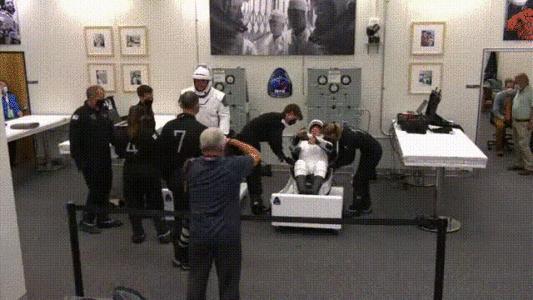 ▲两位宇航员在工作人员的协助下调整宇航服