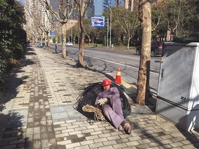 1月10日,上海浦东,午饭时间,一位工人躺在路边休息。新京报记者 罗芊 摄