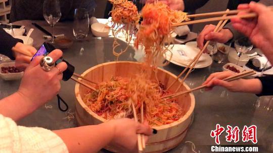 市民体验“捞鱼生”,把鱼生盘中的材料夹得愈高,听说在新的一年中更容易实现心愿。 王子涛 摄