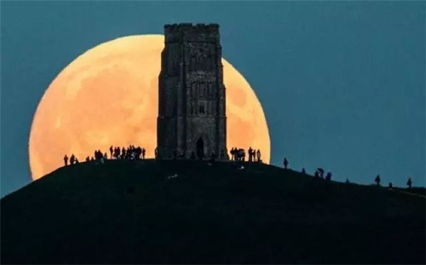 资料图:2015年9月27日,人们在英国格拉斯顿伯里山上观赏超级月亮月食。f7ab69a4.jpg