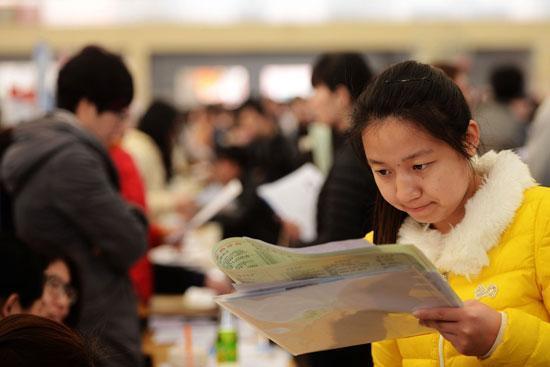 3月19日,山东省青岛市一高校招聘会现场,一名大学生在查看招聘企业资料。