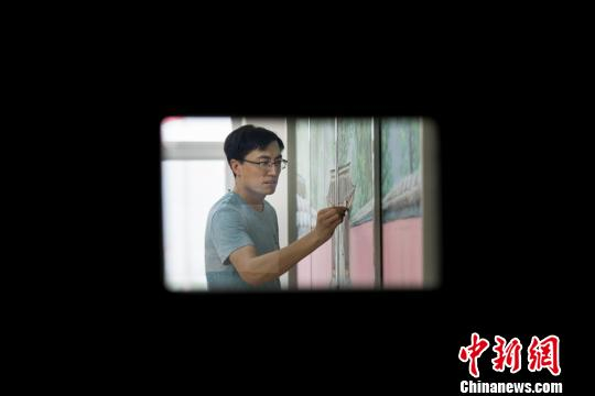 “80后”美术教师赵文瑞正在黑板上完善他创作的一幅名为“红墙绿荫”的粉笔画。　韦亮 摄