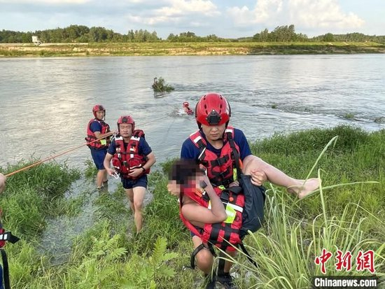 图为消防员将小孩营救上岸。周勉摄