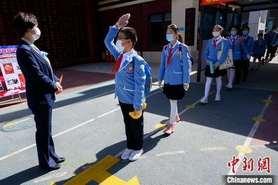 资料图：学生们佩戴口罩进入校园。（图文无关）韦亮 摄