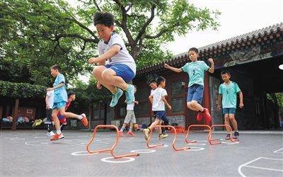 6月11日下午，新鲜胡同小学，上体育课的学生在大树下玩跳格子游戏。 新京报记者 李木易 摄