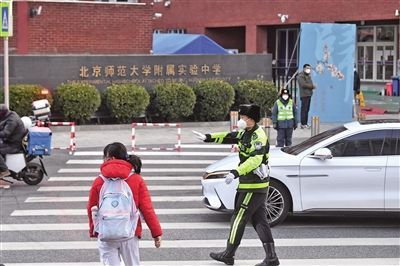 　　2月13日，北京师范大学附属实验中学校门前，交警拦停车辆，让学生优先通过人行横道。本版摄影/新京报记者 王贵彬