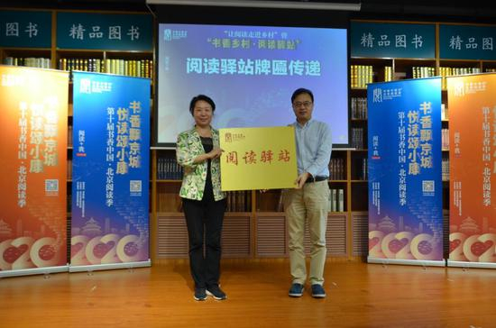 北京联合出版公司总经理张金龙代表主办方为平谷区委宣传部二级调研员王秋芬传递“阅读驿站”牌匾