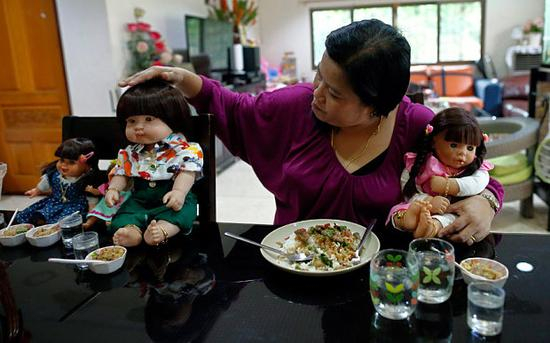 一位泰国妇女和自己的娃娃神一起用餐