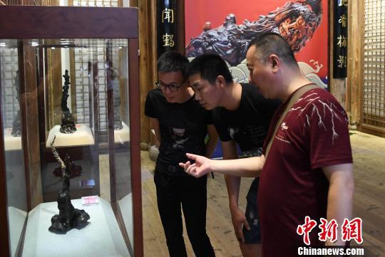 参展艺术家、福建平潭民间海柳雕艺人施孝斌（右一），广东汕头民间海柳雕艺人胡国华（左一）等观展、交流　记者刘可耕 摄