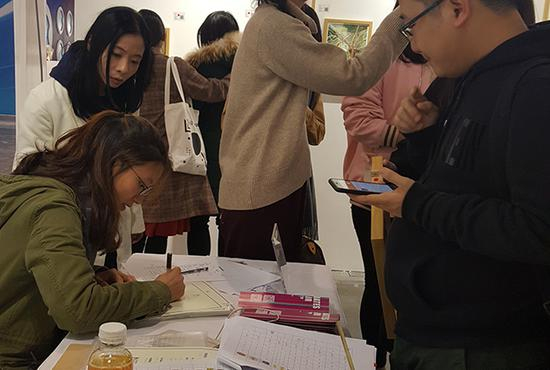 服务台旁的地面，放满了已经被认捐、等待包装的画作——