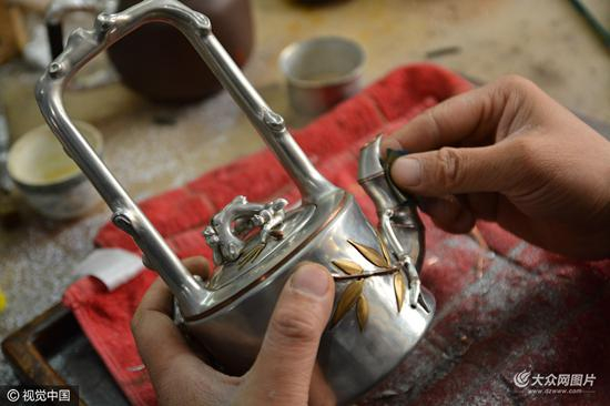 　　唐立果展示他手工打造的一把锡壶。这把名为“三友硬提梁”的锡壶他设计了一年，用时半个月手工制作而成。曾有美国客户出价15000元，他没有卖。