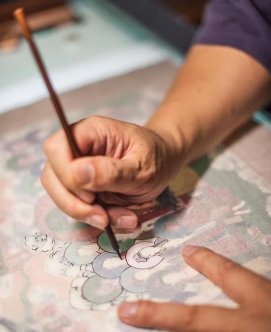 魏立中用薄而半透明的雁皮纸覆在稿子上勾描。