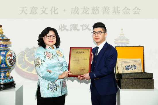 北京成龙慈善基金会副秘书长李海燕展示《盛世升平中国尊》收藏证书
