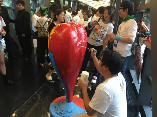 活动参与者在爱心雕塑上写下祝福话语