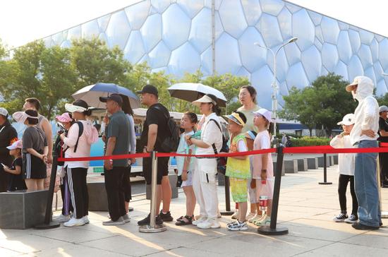 6月23日，旅客在北京奥林匹克公园景不雅正途冒着高温游览。图/中新图片网