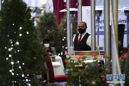 （图片说明：11月6日，在美国纽约，一名侍者在餐厅户外就餐区等待顾客。美国疾病控制和预防中心6日公布的最新数据显示，全美5日报告新增新冠确诊病例117988例，创全球范围内一国单日新增确诊病例数最高纪录；新增死亡病例1135例。来源：新华社记者 王迎 摄）