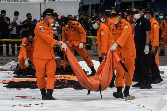  1月10日，搜救人员在印度尼西亚雅加达戈戎不碌港搬运打捞起的失事客机遇难者遗体。（新华社发，阿贡摄）