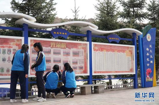 在青海省西宁市湟中区土门关乡初级中学，学生们在活动展板上寻找自己的身影（3月27日摄）。新华社记者 张子琪 摄