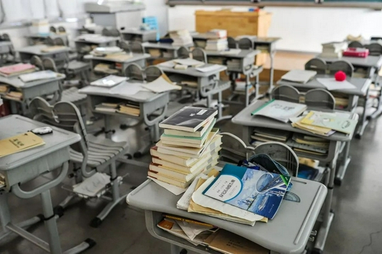  2017年2月24日，北京一家重点中学在房山开设的分校区里，一个上体育课而空出来的教室，课桌上堆满了书本。/视觉中国