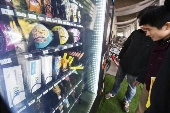 　　2016年11月27日，成都市西南石油大学体育馆附近，一台自动售货机内出现了艾滋病尿样检测包，大学生们正在围观（李小艺 摄 / 视觉中国供图）