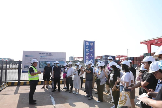 8月17日下午，“港口雄开万里流”网络主题采访团走进山东港口日照港，参观全球首个顺岸开放式全自动化集装箱码头，山东港口日照港集装箱发展有限公司IT部经理徐冠男向记者介绍情况。（摄影记者 修泽旭）