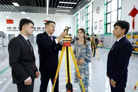 △在塔吉克斯坦首都杜尚别的鲁班工坊内，来自中国天津的老师向学生讲解测绘仪器使用方法（2023年4月12日摄）。