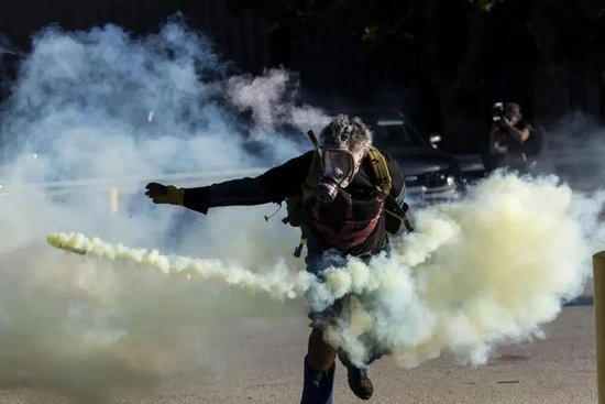 9月26日，在位于美國芝加哥西郊布羅德維尤市的次好移民與海關(guān)執(zhí)法局辦事機構(gòu)外，抗議者在沖突中將執(zhí)法人員發(fā)射的美國內(nèi)戰(zhàn)催淚彈瓶扔回  圖：新華社