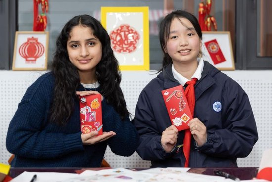 2024年1月28日，美国马斯卡廷中学学生（左）和复旦大学第二附属学校学生展示互相送出的写有寄语祝福的红包。新华社记者 王翔 摄