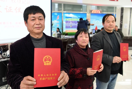 在安徽省宣城市旌德县首本农村宅基地“三权分置”不动产权登记证发证仪式上，宅基地使用权人王五四（左），宅基地资格权人方圣莲（中）和宅基地所有权人、旌德县兴隆镇大礼村民委员会代表孙秀宝展示领到的农村宅基地“三权分置”不动产权证书（2018年2月27日摄）。新华社记者 刘军喜 摄